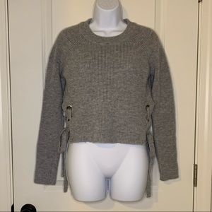 Grey cropped sweater with ties on the sides.